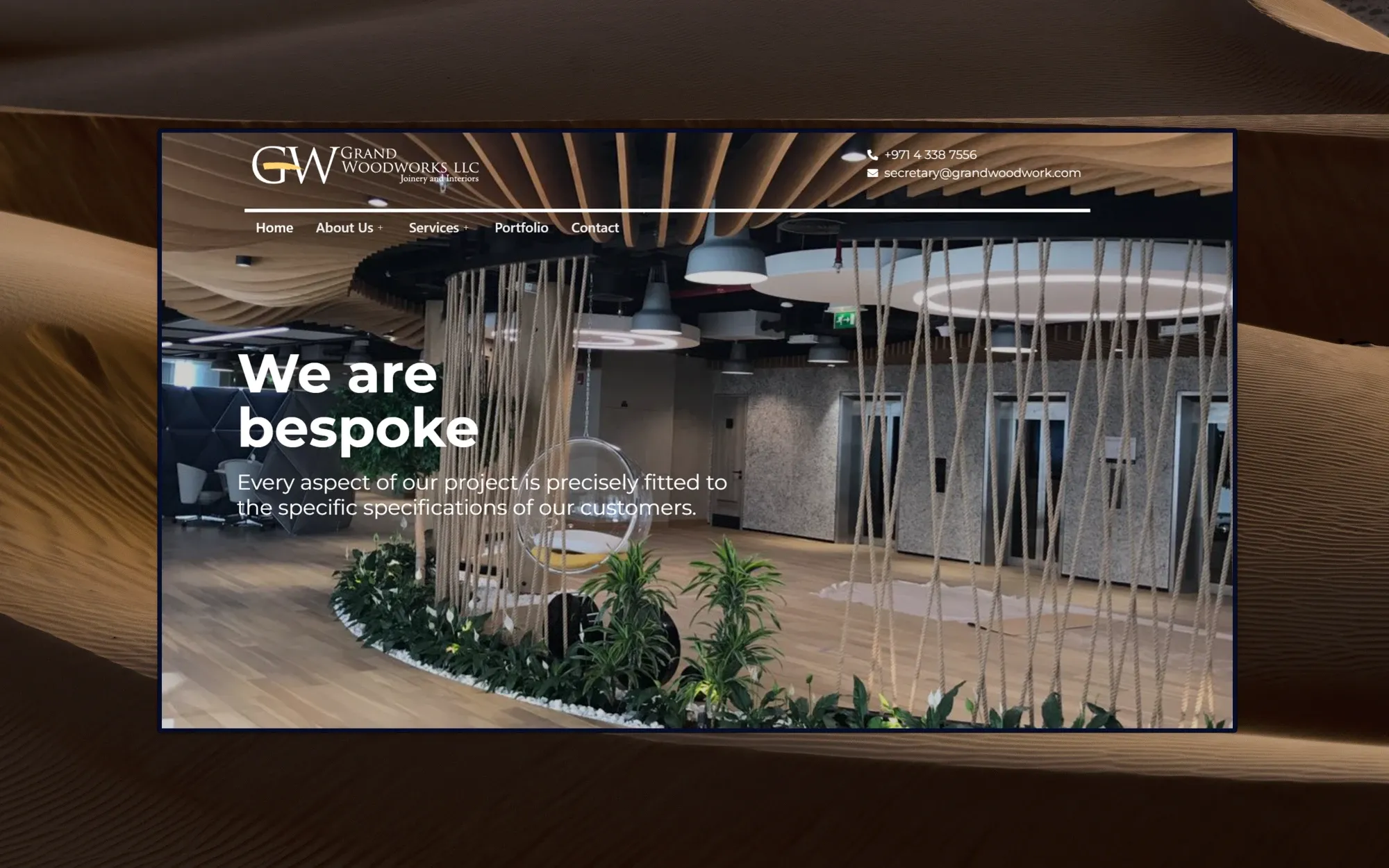 Grand Woodworks homepage: 'We are bespoke' headline over a photo of a fitted office interior with timber ceiling baffles and rope partitions